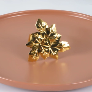 Elegant gold maple leaf napkin ring made of polished alloy on a ceramic tray