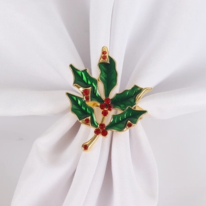 Close-up of a Christmas holly napkin ring with green enamel leaves and red rhinestones