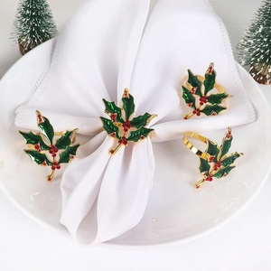 Close-up of holly leaf napkin rings with green enamel and red rhinestones on a table
