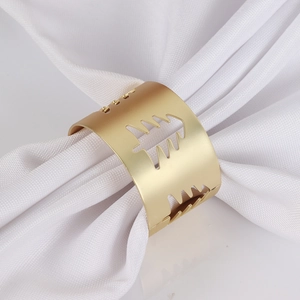 Close-up of matte gold hollow Christmas tree napkin ring on a white napkin