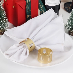 Matte gold Christmas tree napkin ring with hollow design on white fabric napkin