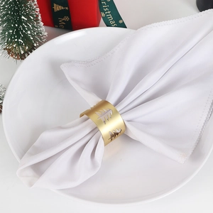 Detail of matte gold hollow Christmas tree napkin ring on white plate with festive decor