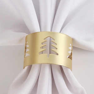 Detail of matte gold Christmas tree cutout napkin ring on a white cloth napkin