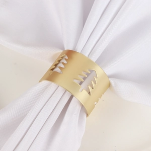 Detail of matte gold hollow Christmas tree napkin ring on white fabric napkin
