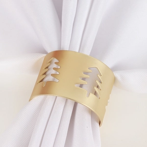 Macro view of matte gold Christmas tree cutout napkin ring on white fabric napkin