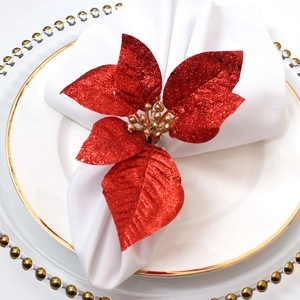 Christmas poinsettia napkin ring with red glitter petals and gold core on white cloth