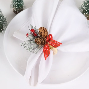 Detailed view of Christmas napkin ring with wooden base, pine cones, red berries and bell