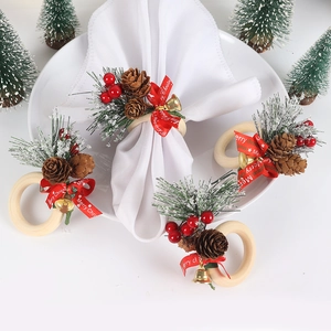 Detail of Christmas napkin rings with wood loops, pine cones, red berries and gold bells
