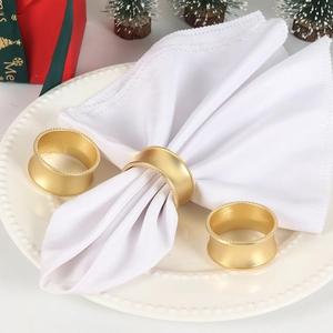 Ronds de serviette dorés mats avec bords perlés sur une assiette de fête