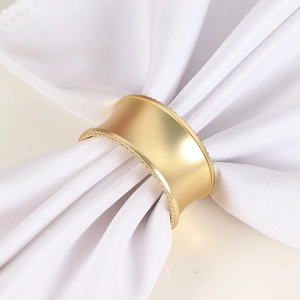 Détail du rond de serviette doré mat avec bordure perlée sur tissu blanc pour mariage