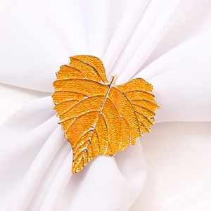 Golden leaf napkin ring with detailed vein textures on white fabric setting