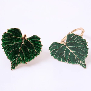 Set of 2 artificial green leaf napkin rings with golden metal edges on white background
