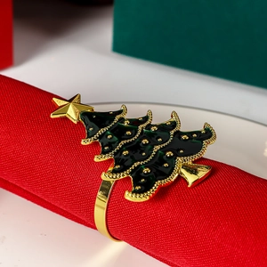 Detailed macro view of a green enamel Christmas tree napkin ring with gold star on red fabric