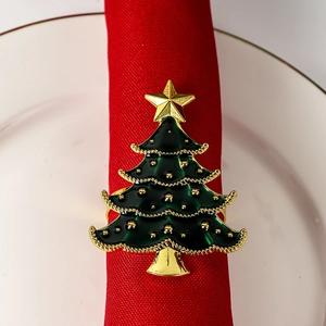 Detail of green enamel Christmas tree napkin ring with gold star on a red napkin