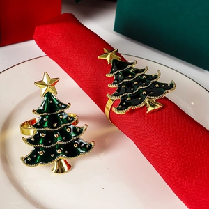 Detail of Christmas tree napkin ring with green enamel and gold star on red napkin