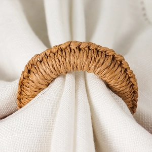 Handwoven rustic jute napkin ring with natural fiber texture on white linen cloth