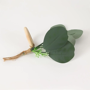 Dettaglio dell'anello portatovagliolo in legno con foglie di eucalipto e fiori