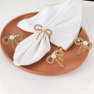 Set of four gold bowknot napkin rings with sparkling rhinestones and white pearls