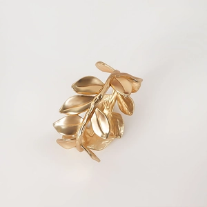 Macro view of matte gold leaf napkin ring with intricate metal plated branch textures
