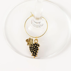 Macro detail of golden grape wine glass charm marker on a transparent stemware base