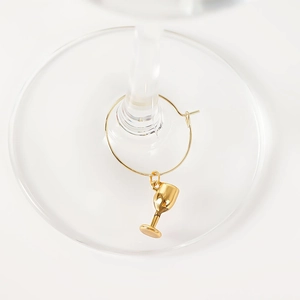 Detail of gold wine glass charm with goblet pendant on a clear glass base