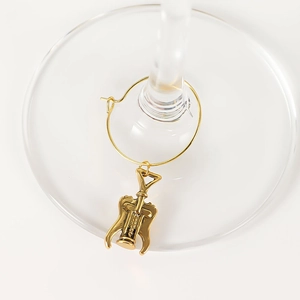 Close-up of golden wine glass charm with a miniature corkscrew pendant on a glass stem