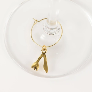 Detailed view of a golden wishbone wine glass charm on a transparent glass base