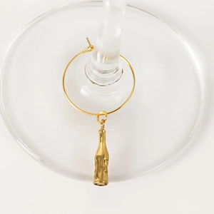 Detailed close-up of a golden wine bottle charm marker hanging on a glass stem