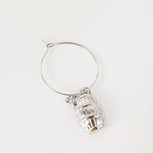 Macro shot of silver metal wine glass charm featuring a textured barrel pendant