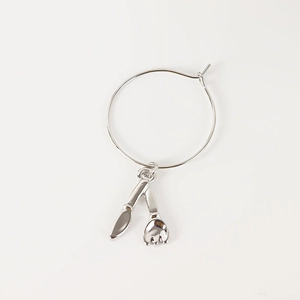 Macro detail of silver cutlery charms with knife and fork pendants on circular wine glass rings