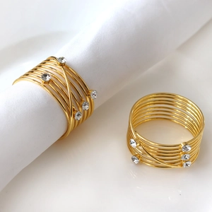 Detail of spiral gold napkin rings with diamond accents and multi-layer metallic wrap
