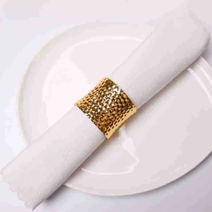 Macro shot of gold hammered metal napkin ring on a white cloth for table setting
