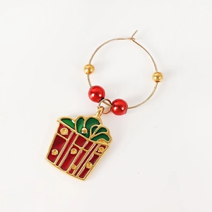 Macro detail of Christmas wine glass charm with festive red gift box pendant and beads