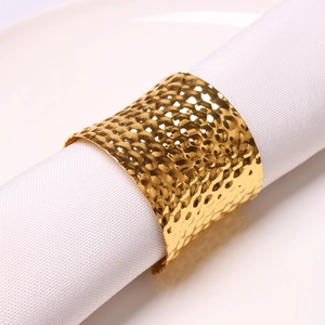 Minimalist gold alloy napkin ring with hammered texture on white cloth for hotel banquets