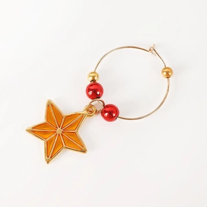 Detailed view of Christmas wine glass charm featuring a golden star and red beads
