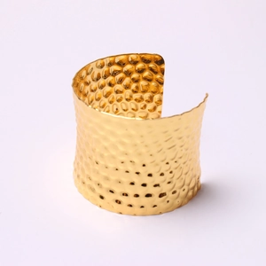 Wide hammered gold metal cuff bracelet with C-shaped open design on white background