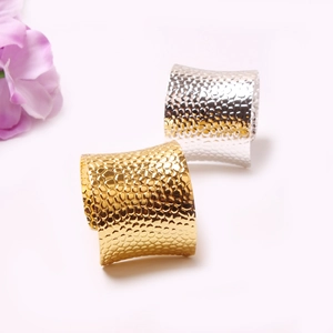 Close-up of gold and silver napkin rings with textured hammered metal finish