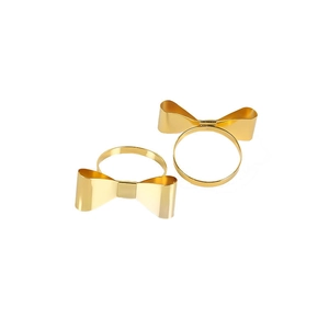 Detail of two golden bowknot napkin rings with mirror polished metal surface on white background