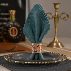 Detail of rose gold hollow napkin ring with Hebrew festive text and green fabric