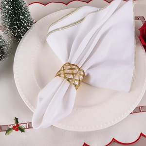 Handmade gold wire mesh napkin ring on a white napkin with festive Christmas backdrop