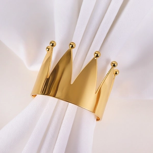 Macro shot of gold crown napkin ring with polished metal finish on white fabric