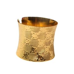 Golden wide cuff bracelet with engraved butterfly pattern and textured finish