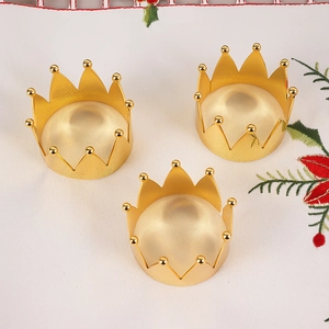 Three golden crown napkin rings on floral embroidery fabric for wedding table decor