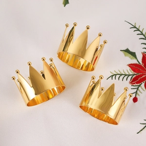 Three-piece gold crown napkin rings set on white festive fabric for wedding banquets