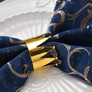 Macro shot of a polished golden crown napkin ring on a blue patterned napkin