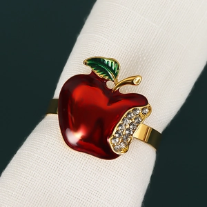 Detail of red apple napkin ring with crystals and gold finish on white cloth