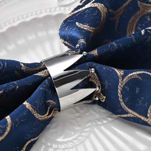 Macro shot of crown napkin ring in polished silver metal on dark blue napkin