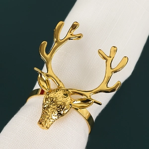 Detail of a golden reindeer napkin ring with antlers on a white linen napkin