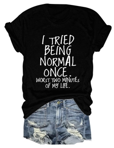 Détail du t-shirt noir imprimé avec slogan et short en jean déchiré sur fond blanc épuré