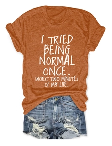 Détail du slogan imprimé blanc sur un t-shirt en coton orange avec short en jean